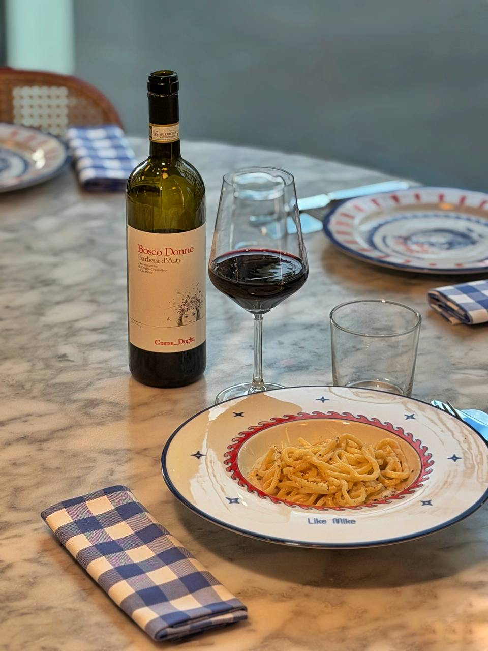 Un piatto di pasta e un bicchiere di vino al tavolo di Like Mike